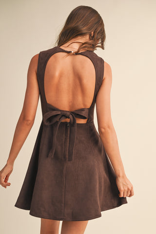 Brown dress with open back and bow detail on a beige background
