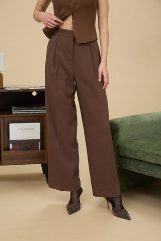 Person wearing a brown outfit with wide-leg pants in a room setting.