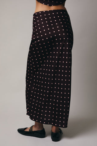 Black skirt with white polka dots worn by a person on a plain background
