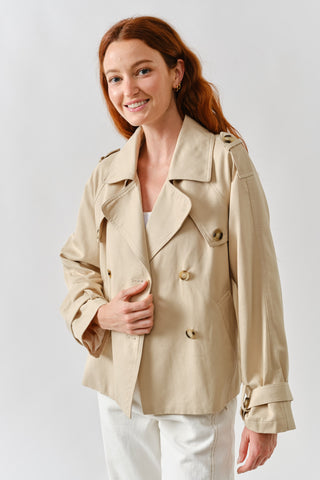 Woman wearing a beige trench coat on a plain background