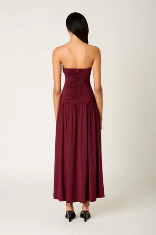 Woman wearing a burgundy strapless dress on a white background