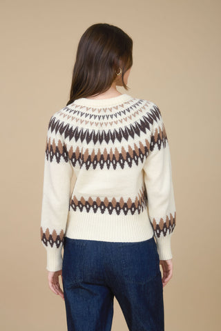 Person wearing a patterned sweater with a beige background