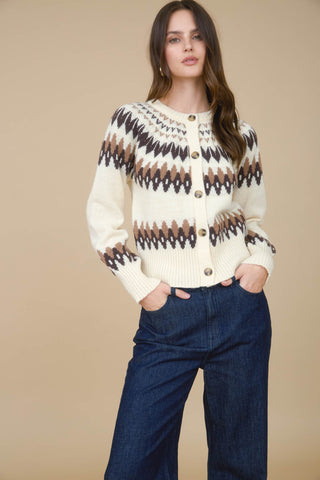 Woman wearing a patterned sweater and jeans against a beige background