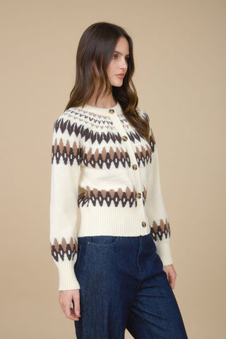 Woman wearing a patterned sweater and blue jeans against a beige background