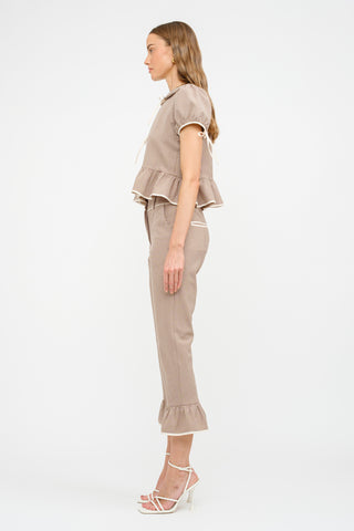 Side view of taupe gingham printed blouse with tie-front detailing, offering a flattering, relaxed fit. Showing tie puff sleeve. Pairs perfectly with the matching Nelly Gingham Pant for a coordinated look. Model is wearing a size small.