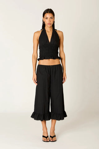 Woman wearing a black halter top and wide-leg pants on a white background