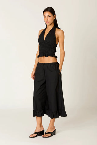 Woman wearing a black halter top and wide-leg pants on a white background