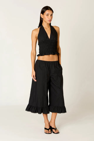 Woman wearing a black halter top and wide-leg pants on a white background