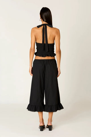Person wearing a black halter top and wide-leg pants on a white background