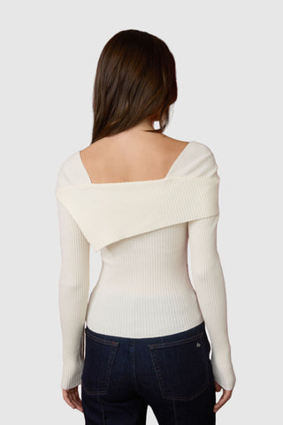 Woman wearing a cream-colored sweater with a unique back design on a white background