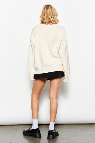 Person wearing a cream sweater and black skirt against a white background