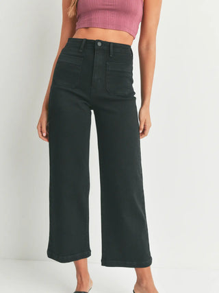 Person wearing black wide-leg jeans and a pink crop top on a white background