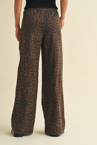 Leopard print pants worn by a person on a beige background