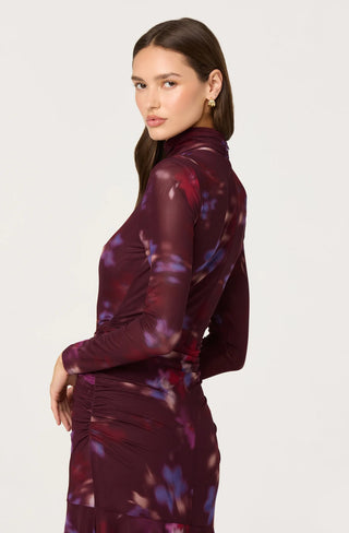 Woman wearing a burgundy dress with floral patterns on a white background