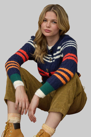 Woman wearing a colorful striped sweater sitting on a patterned rug.