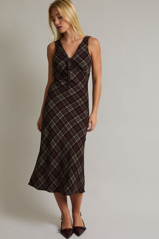 Woman wearing a plaid dress against a plain background