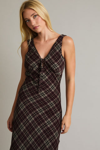 Woman wearing a plaid dress against a plain background