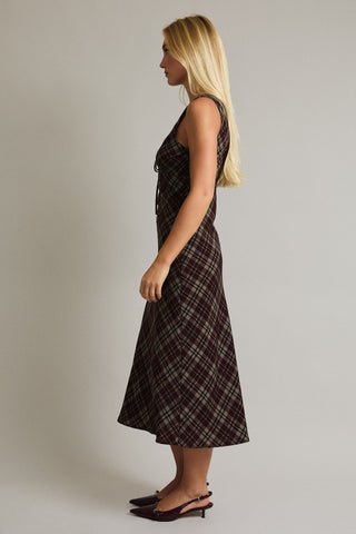 Woman wearing a plaid dress against a plain background