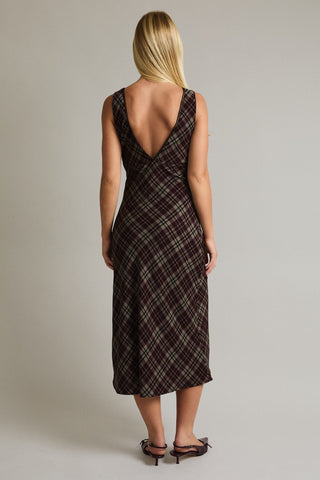 Woman wearing a plaid dress with an open back on a plain background