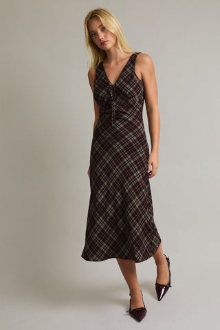 Woman wearing a plaid dress against a plain background