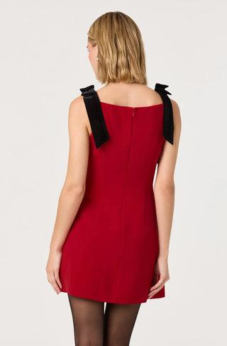 Red dress with black bow straps worn by a model on a white background