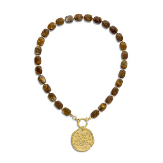 A beaded necklace made of brown translucent stone beads with a gold-toned coin pendant, displayed on a clean white background.