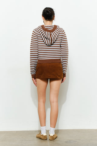 Person wearing a striped sweater and brown shorts against a white background