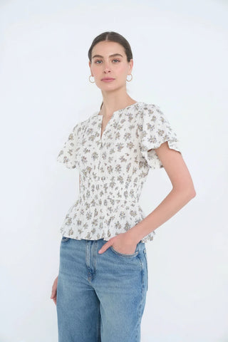Woman wearing a floral blouse and blue jeans against a white background