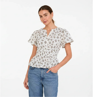 Woman wearing a floral blouse and blue jeans against a red background