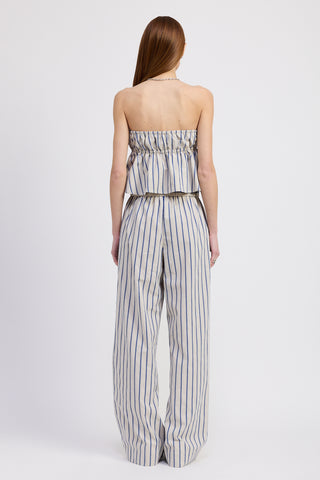 Back view of a woman wearing a strapless blue and white striped tube top paired with matching wide-leg pants, standing against a white backdrop