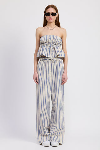 Woman wearing a strapless blue and white striped tube top paired with matching drawstring pants and sunglasses, standing against a white backdrop