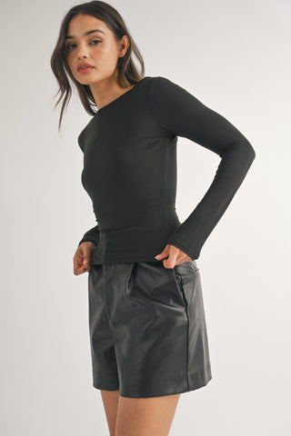 Woman wearing a black long-sleeve top and gray shorts on a white background