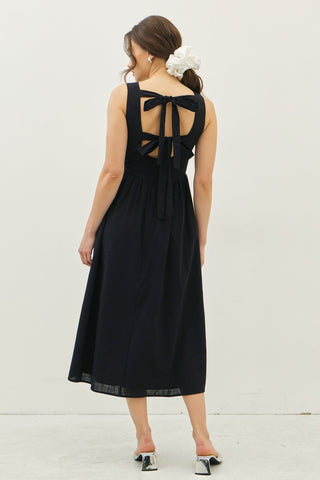 Back view of black cotton midi dress with bow tie detailing and open-back cutouts