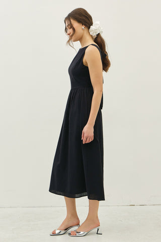 Side profile of black cotton midi dress featuring a sleeveless bodice and soft gathered skirt