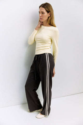 Woman wearing a yellow top and black pants with white stripes against a white background