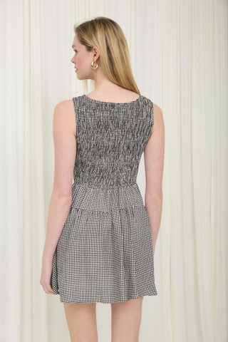 Woman wearing a black and white checkered dress against a white curtain background