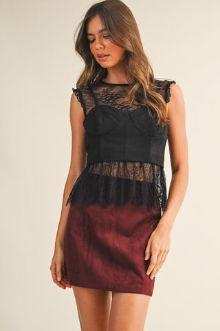 Woman wearing a black and burgundy dress with lace details on a beige background