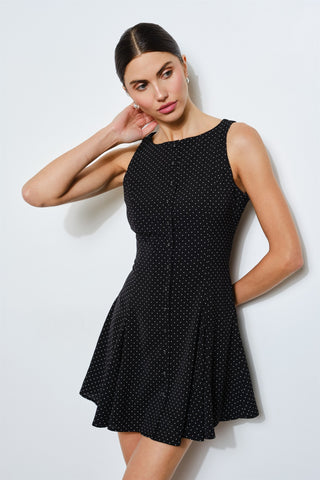 Woman wearing a black fitted polka dot dress against a white background 