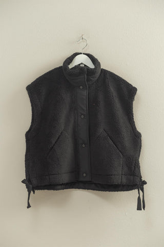 Black vest on a hanger against a beige wall