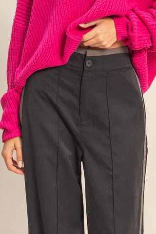 Person wearing a bright pink sweater and black pants on a beige background