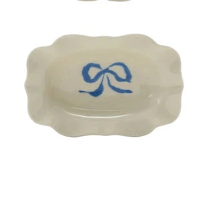 Four small ceramic dishes with colorful bow designs on a white background