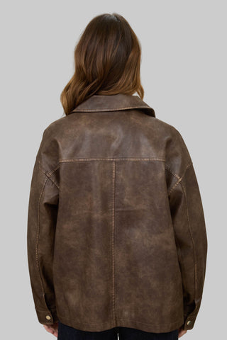 Person wearing a brown leather jacket in a room with a red lamp.