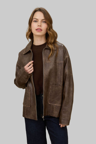 Woman wearing a brown leather jacket on a gray background
