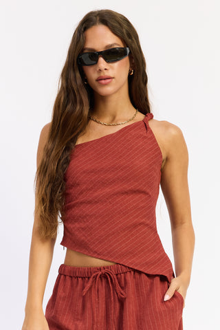 A woman modeling a rust-red textured halter crop top and matching drawstring shorts against a clean white background.