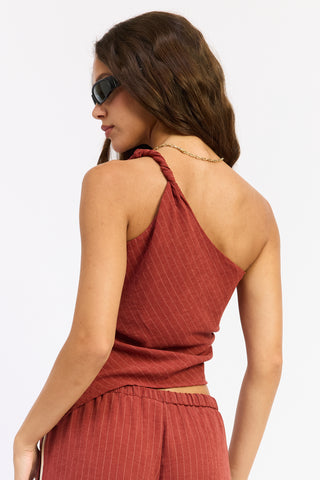 Woman wearing a rust-colored halter top and pants on a white background