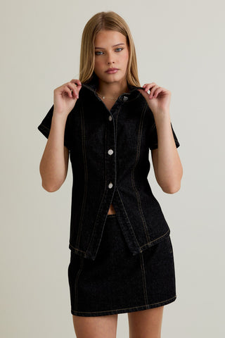 Woman wearing a black denim dress against a plain background