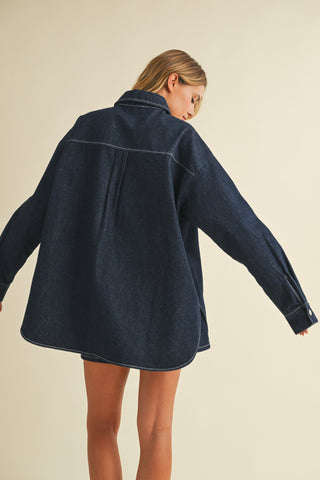 Person wearing a dark blue denim jacket on a beige background