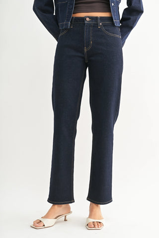 Dark blue jeans worn by a person on a white background