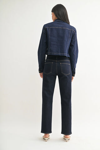 Person wearing a dark blue denim jacket and jeans on a white background