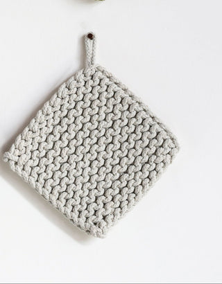 Four knitted pot holders in brown, green, black, and gray on a white background